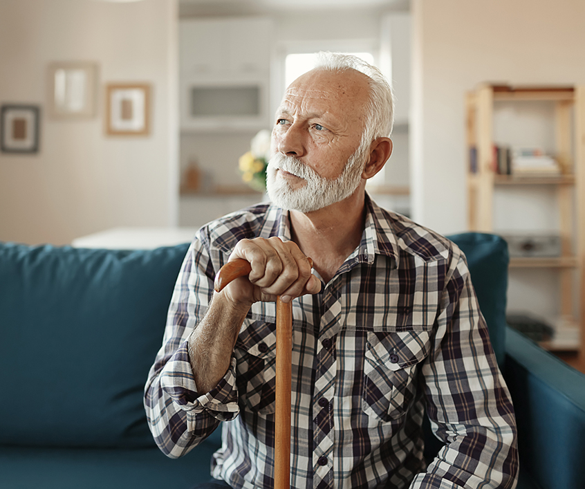 Portrait of a senior man, holding a cane, looking thoughtfully into the distance