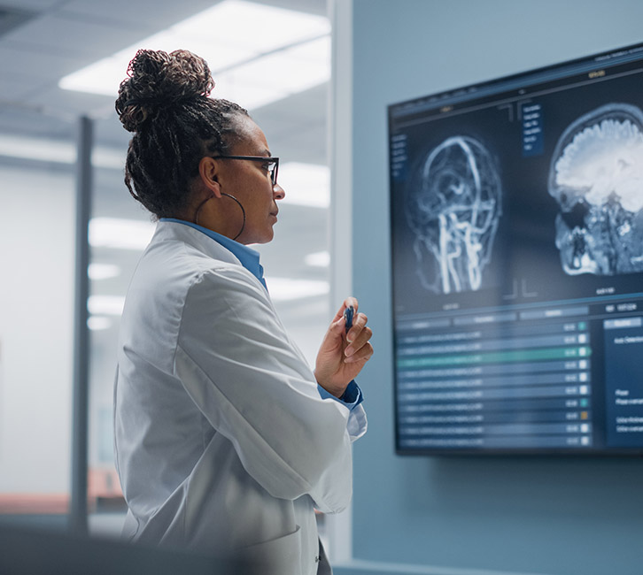Black female scientist, in clinical setting, is shown studying neuro imaging